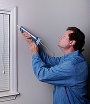 Applying caulking to stop drafty windows.